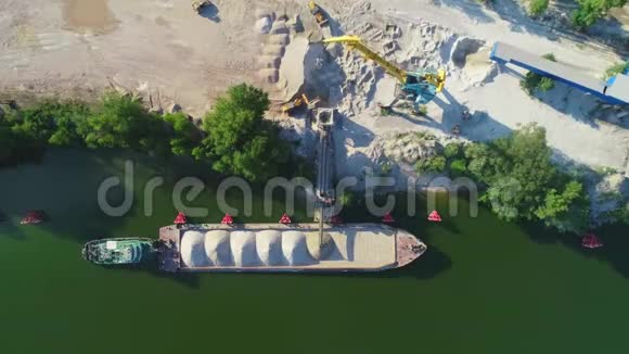 起重机正在将沙子和砾石装载到驳船上进行河流运输空中无人机视频的预览图