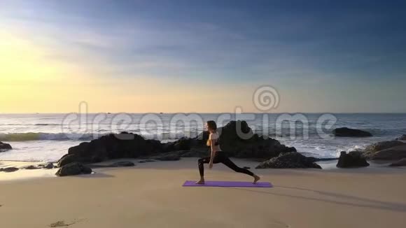 金发女郎在海边和岩石海滩练习瑜伽视频的预览图