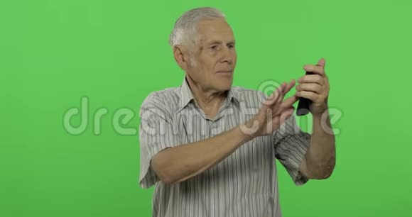 老人用智能手机说话性感钥匙背景上英俊的老人视频的预览图