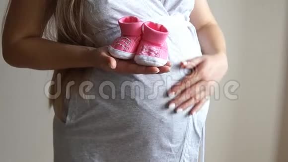 抱着婴儿鞋的孕妇怀孕的女孩女孩抚摸怀孕的肚子视频的预览图