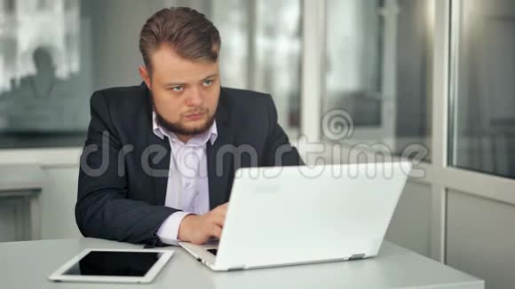 年轻商人在办公室工作坐在办公桌前看着笔记本电脑屏幕视频的预览图