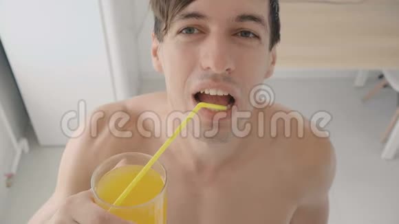 在炎热的夏天年轻人在厨房里用管子喝着清爽的橘子汽水视频的预览图