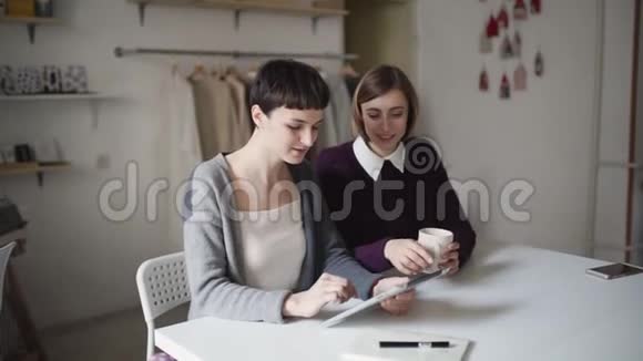 两位有创意的女士用平板电脑做背景挂衣服的新项目视频的预览图
