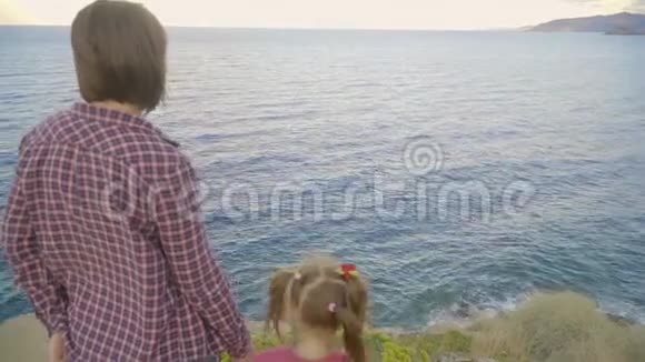 母女俩站在一座山顶上望着大海日落视频的预览图