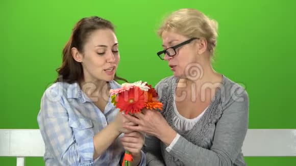 和她母亲在一起的女孩正在闻一束花绿色屏幕视频的预览图
