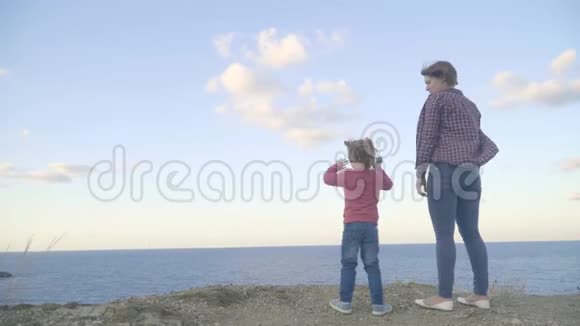 母女俩站在一座山顶上望着大海日落视频的预览图