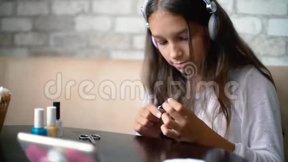 可爱的女孩戴着耳机在网上聊天用免费和复制的空间制作指甲抛光指甲视频的预览图
