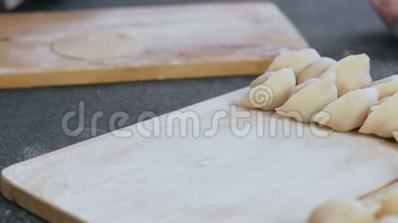 女人用肉馅包饺子特写的手把饺子放在木板上视频的预览图