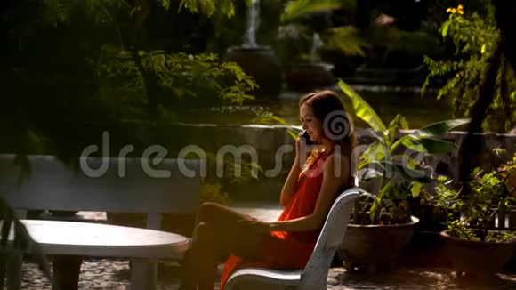 女人在花园里对着喷泉打电话视频的预览图