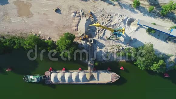 起重机正在将沙子和砾石装载到驳船上进行河流运输空中无人机视频的预览图