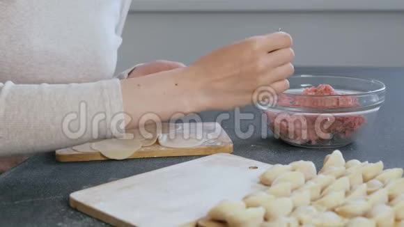 女人用肉馅包饺子特写的手侧视视频的预览图