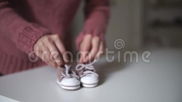妈妈的手在玩粉红色的婴儿鞋为婴儿编织衣服视频的预览图