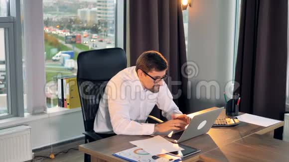 一个商人在笔记本电脑上打字并在沮丧中销毁纸张视频的预览图