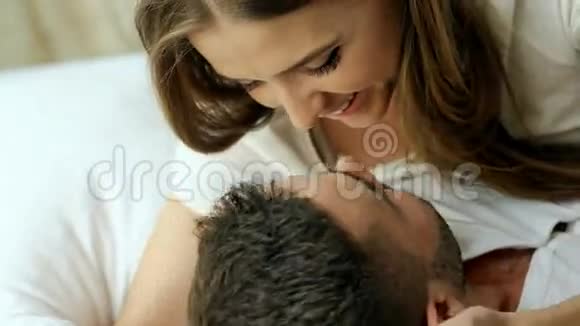 一对年轻美丽有爱心的夫妇早上在床上玩耍和接吻迷人的男人亲吻拥抱他视频的预览图