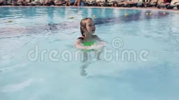一个小女孩在避暑胜地的游泳池里游泳视频的预览图