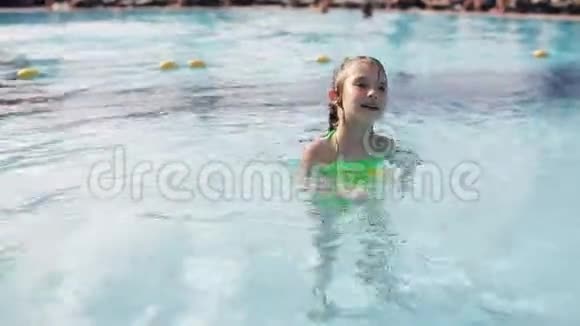 一个小女孩在避暑胜地的游泳池里游泳视频的预览图