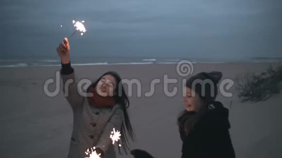 两个女孩晚上在海滩上举行烟火视频的预览图