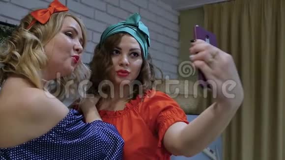 两个漂亮的女人穿着针式的衣服金发碧眼的黑发美女在智能手机上自拍视频的预览图