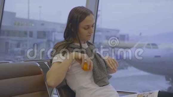 年轻女子坐在机场伸展身体背景是飞机视频的预览图