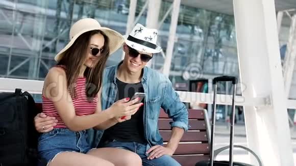 旅行情侣使用电话坐在机场航站楼附近视频的预览图