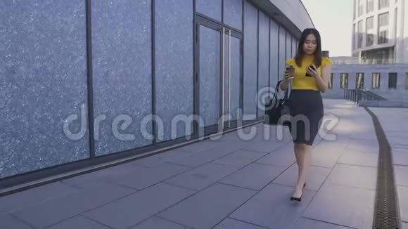 亚洲商界女性拿着电话和咖啡走路视频的预览图