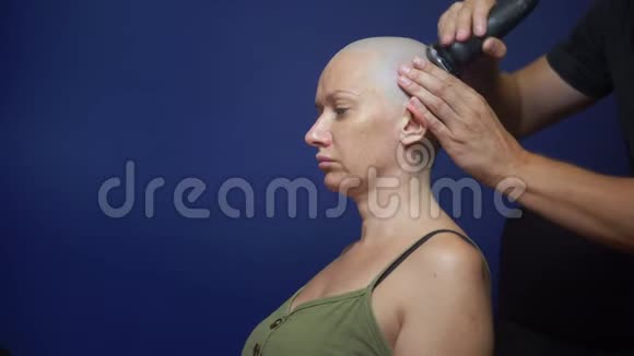 男人用蓝色背景的电动剃须刀剃光头女人化疗效应的概念视频的预览图