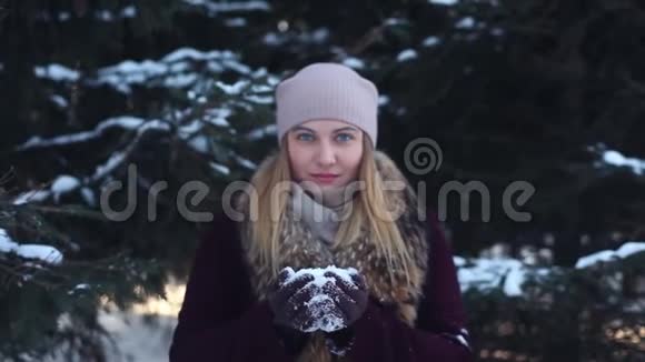 美丽的女孩用手吹雪享受大自然视频的预览图