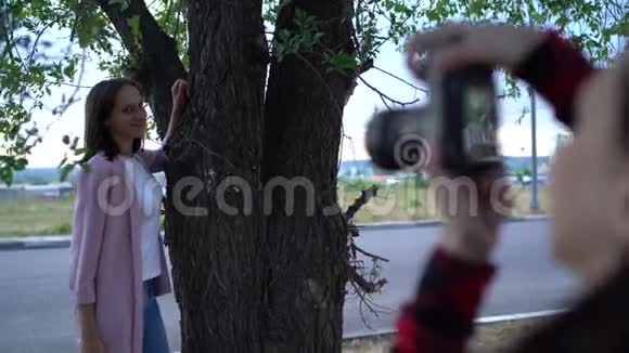 女孩摄影师在阴天在公园里拍摄一个女人视频的预览图