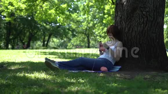 小女孩在公园的树下编织视频的预览图