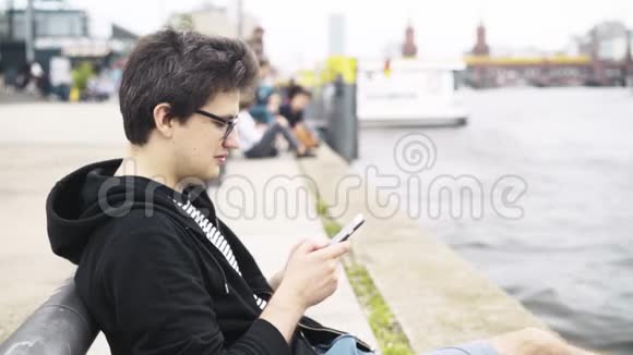 穿短裤的年轻人坐在德国奥伯鲍姆桥附近发短信视频的预览图