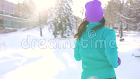 布鲁内特女孩在一个阳光明媚的冬日在城市的汽车背景下慢跑视频的预览图