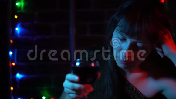 一位忧郁的年轻女子晚上喝红酒的肖像视频的预览图