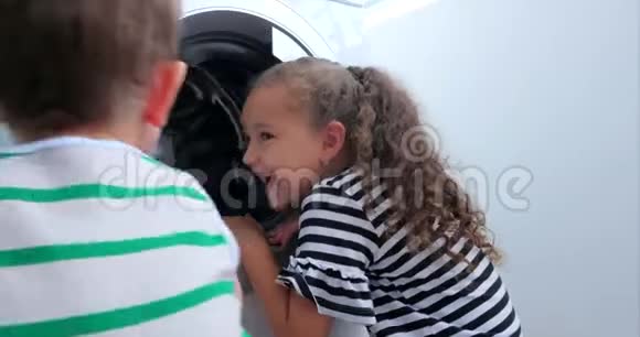 可爱的孩子们看着洗衣机里面气缸旋压机工业概念洗衣机视频的预览图