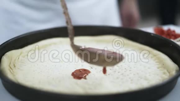 厨师用勺子把番茄酱倒在披萨上视频的预览图