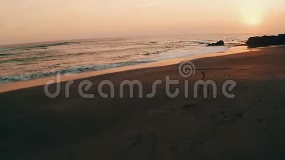 在日落时分穿着连衣裙戴着帽子在沙滩上放松视频的预览图