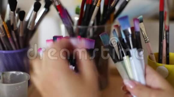 女人选择画笔作画艺术观念画室里有很多刷子用刷子把手收起来视频的预览图
