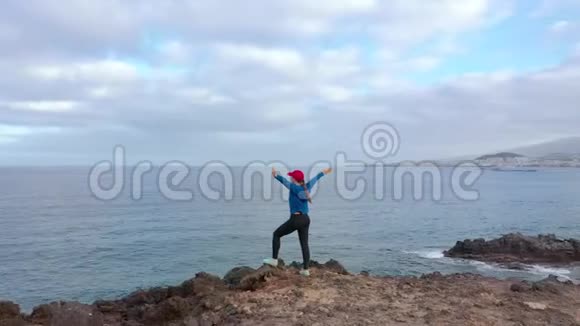 慢跑后穿运动服的女士站在岩石上欣赏保护区的风景视频的预览图