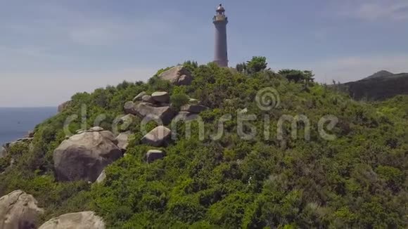 青山上的海上灯塔和岩石海岸无人驾驶飞机景观在山崖和绿松石上的鸟瞰灯光视频的预览图