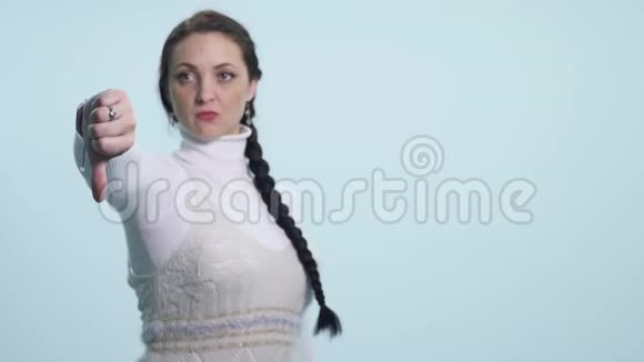 女人用拇指向下做手势看着白色背景下的消极表情和不赞同视频的预览图