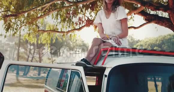 在阳光明媚的4k天女人在车顶上放松视频的预览图