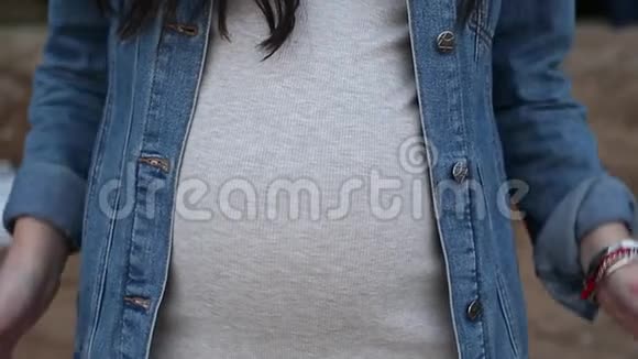 女性触摸怀孕的腹部用手指做心脏的象征视频的预览图