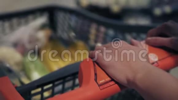 无法辨认的女性手推着购物车在杂货店视频的预览图