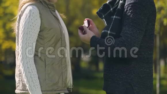 年轻人建议女朋友戴戒指在秋天公园订婚恋爱视频的预览图