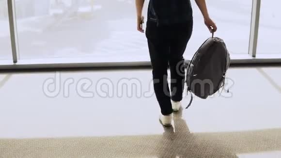 带背包的女人走到机场窗口快乐成功的欧洲乘客女孩与智能手机在终点站4K视频的预览图
