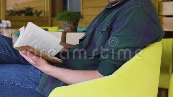 穿绿色衬衫的人在咖啡馆看书视频的预览图