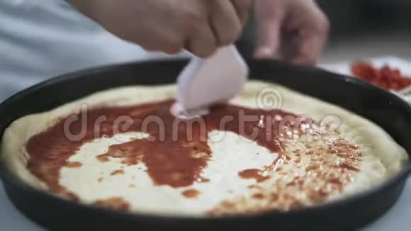 厨师用刷子在披萨上撒番茄酱视频的预览图