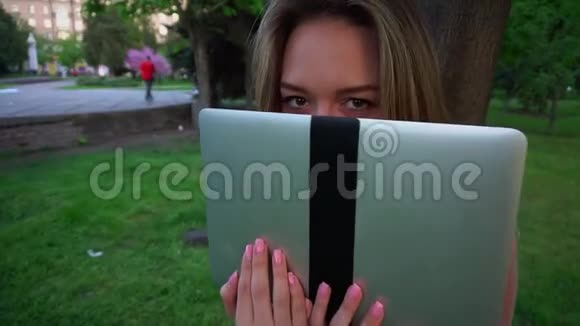 在花园的笔记本电脑附近闭上女孩移动眉毛的眼睛视频的预览图