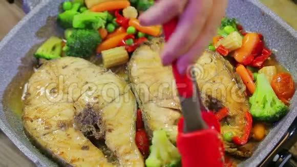 烤架的火钳在锅里炒蔬菜和烤鱼视频的预览图