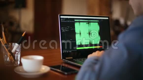 声音设计师或工程师在笔记本电脑上工作有音频掌握软件屏幕上有波形听着贾曼视频的预览图