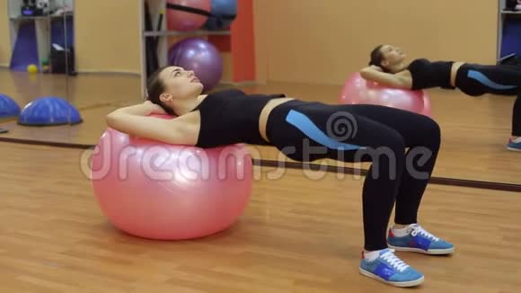 运动女孩在健身房里用健身球来挥动压力视频的预览图